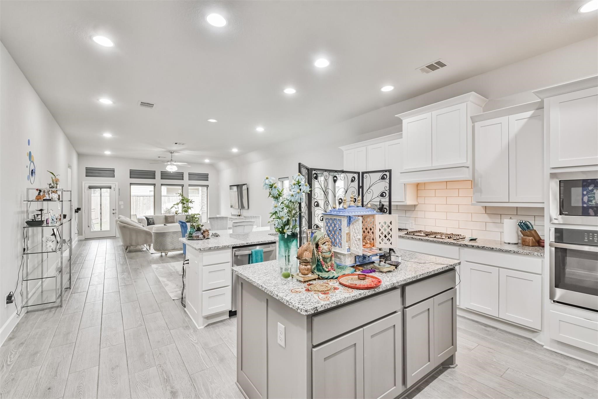 15018 Concho River Way Cypress, TX 77433 - Photo 6 of 34 a kitchen with a sink dishwasher stove and white cabinets with wooden floor
