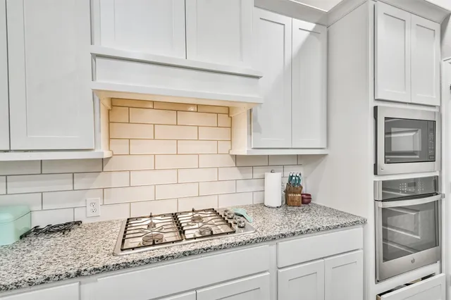 a kitchen with granite countertop white cabinets and stainless steel appliances