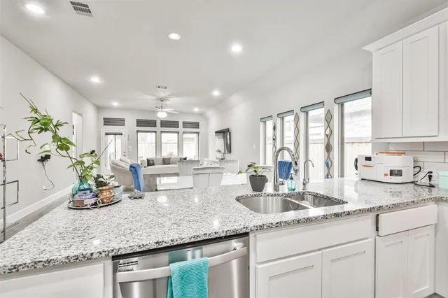 a kitchen with sink stove and white cabinets with wooden floor