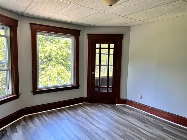 a view of an empty room with wooden floor and a window