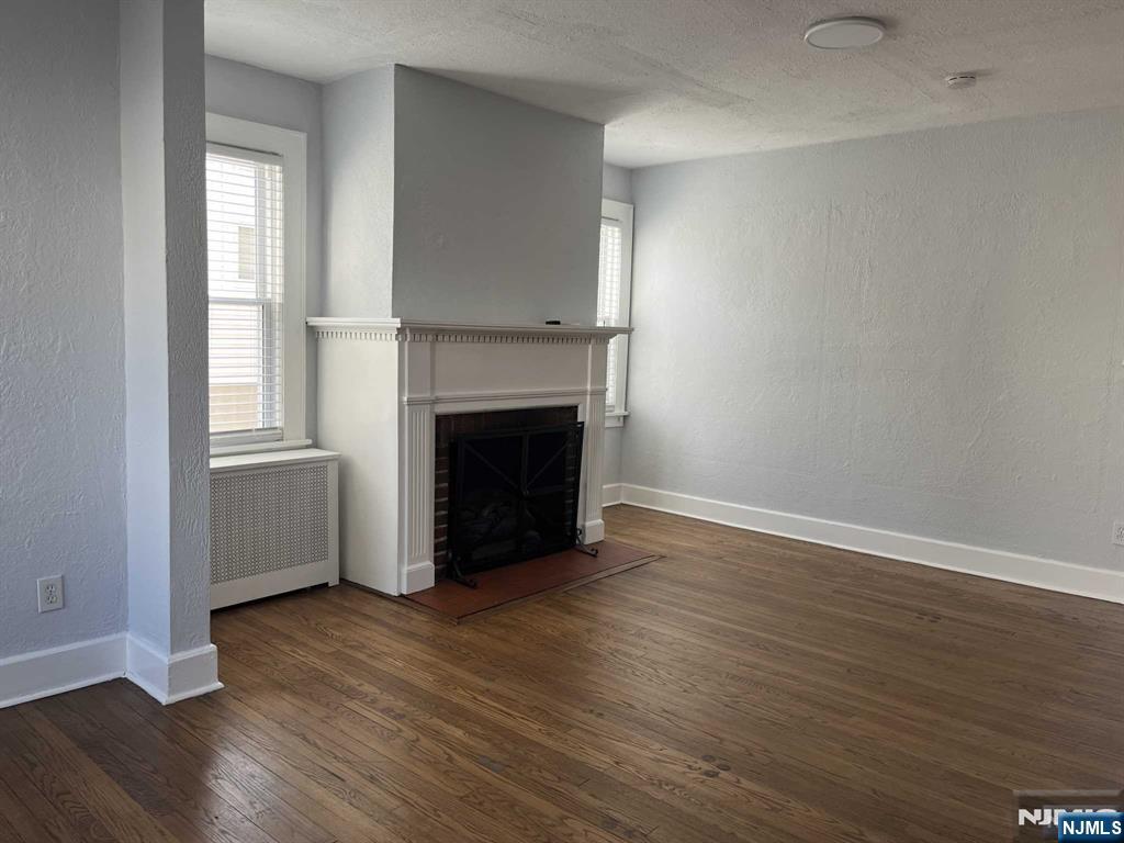 212 Walton Street, Unit 2 Ridgewood, NJ 07450 - Photo 11 of 27 an empty room with wooden floor and fireplace