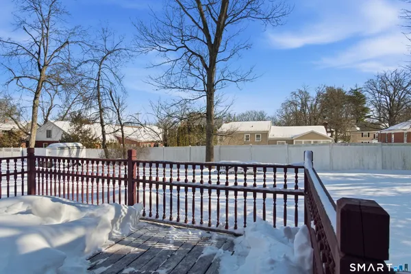 a view of a brick house with large trees and wooden fence