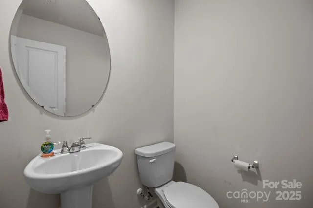 a bathroom with a granite countertop sink a toilet a mirror and shower curtain