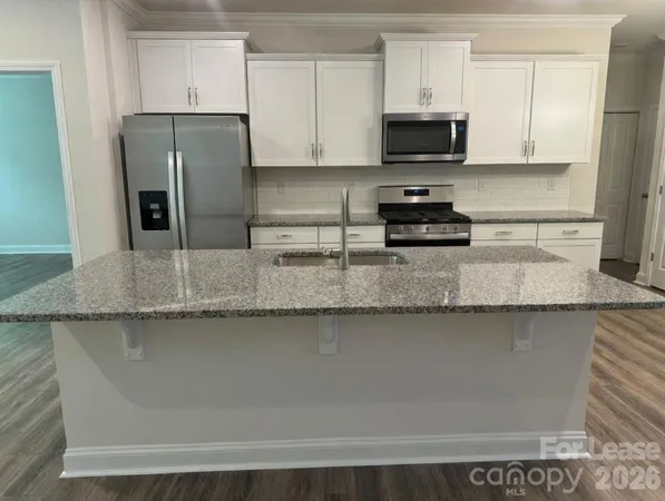a kitchen with granite countertop a refrigerator and a stove top oven