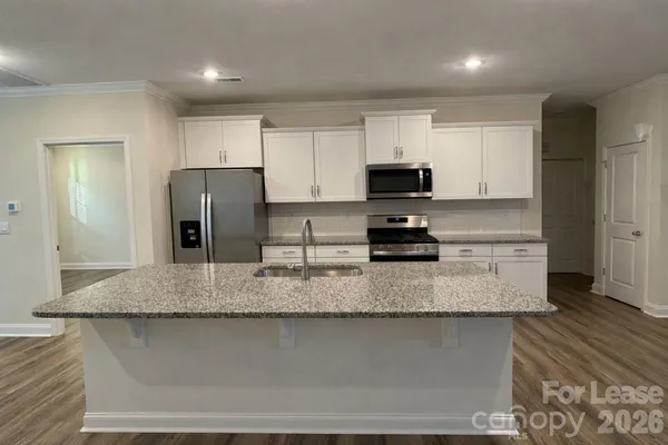 a kitchen with stainless steel appliances granite countertop a sink a stove a refrigerator a microwave and cabinets