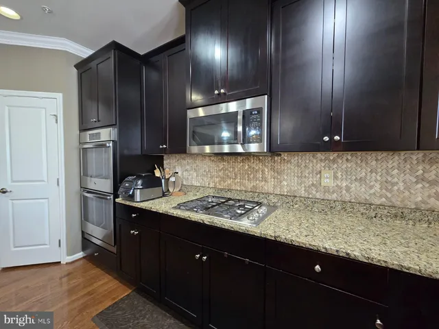 a kitchen with kitchen island granite countertop wooden cabinets and refrigerator