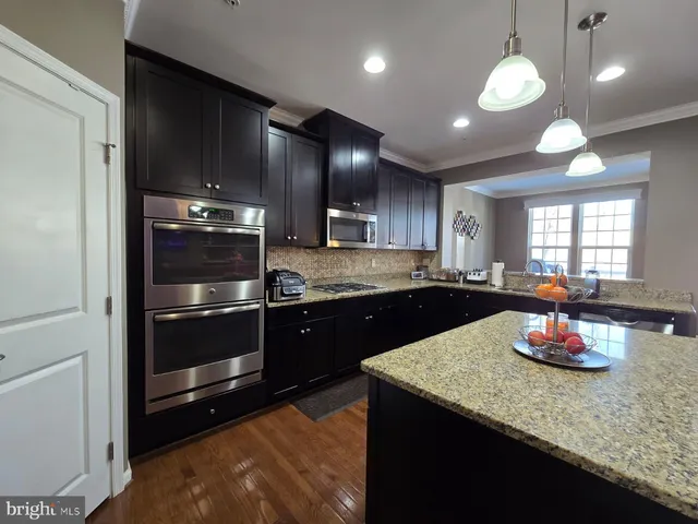 a large kitchen with a large counter top space a sink and stainless steel appliances