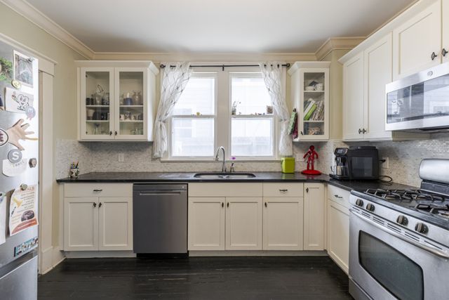 a kitchen with granite countertop white cabinets and a window