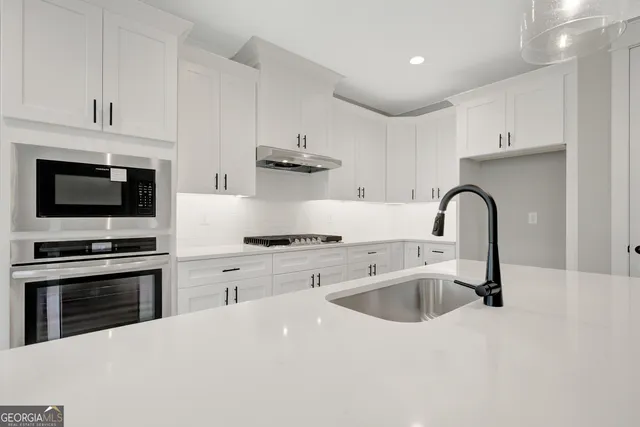 a kitchen with stainless steel appliances kitchen island a stove a sink and a microwave