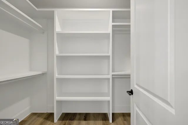 a walk in closet with wooden floor