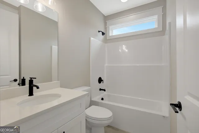 a bathroom with a sink a toilet a mirror and shower