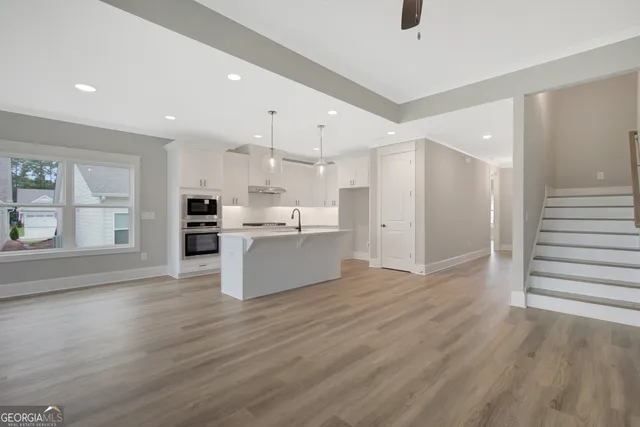 a large kitchen with stainless steel appliances kitchen island a large counter top and a wooden floors