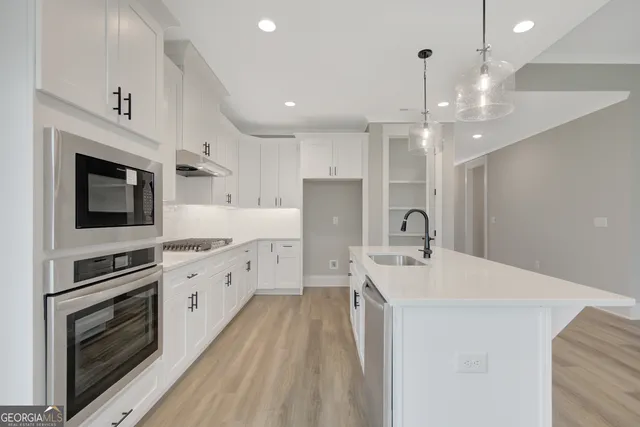 a large kitchen with stainless steel appliances a stove sink and cabinets