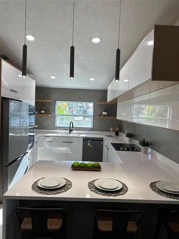 a kitchen with stainless steel appliances a sink a stove a center island and chairs