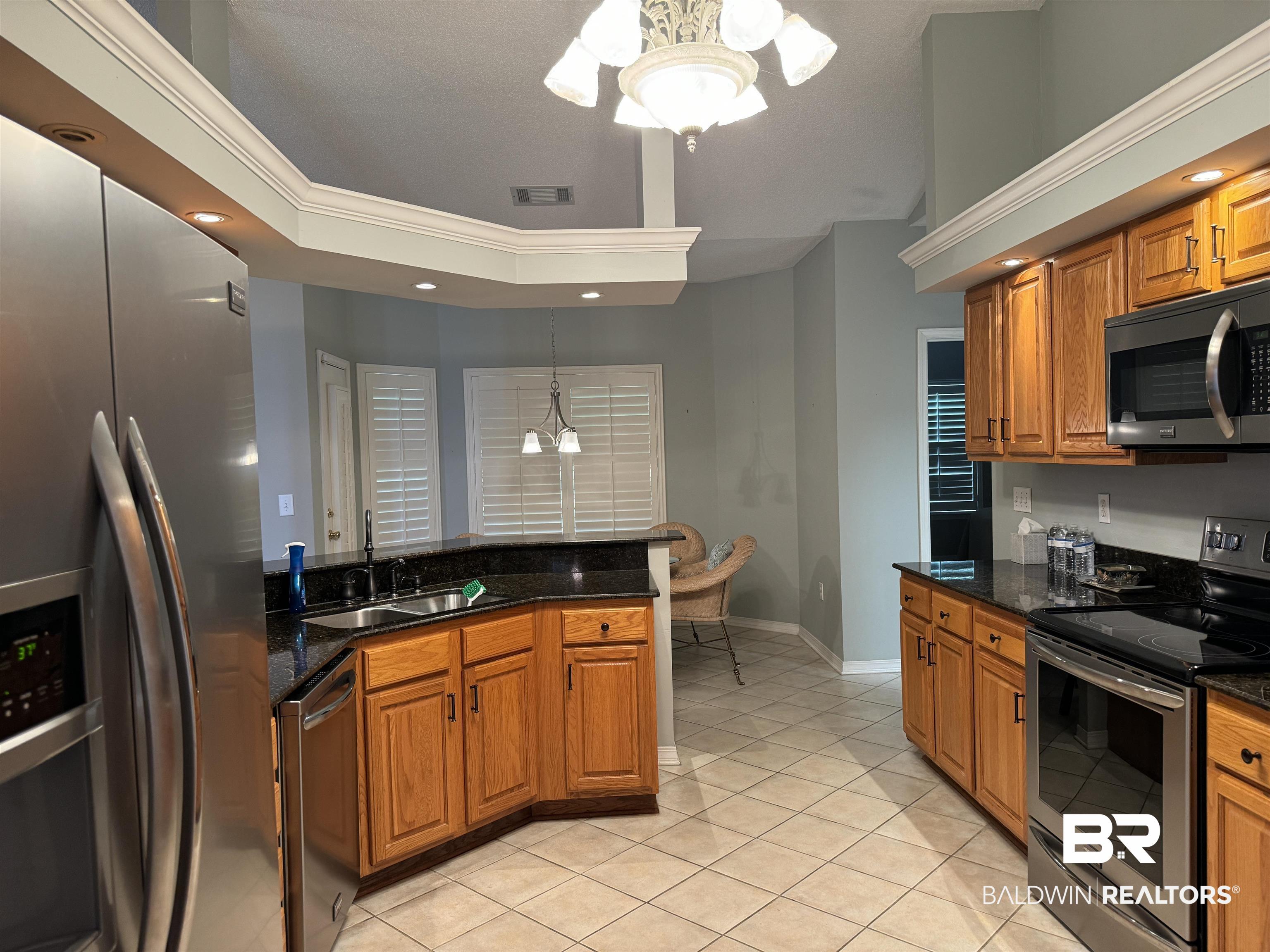 9139 Clubhouse Drive Foley, AL 36535 - Photo 15 of 30 Kitchen with appliances with stainless steel finishes, dark stone counters, an inviting chandelier, sink, and hanging light fixtures