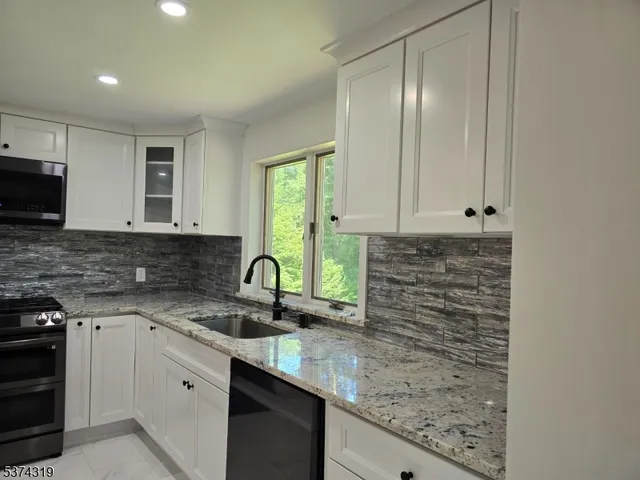 a kitchen with granite countertop a sink a stove and cabinets