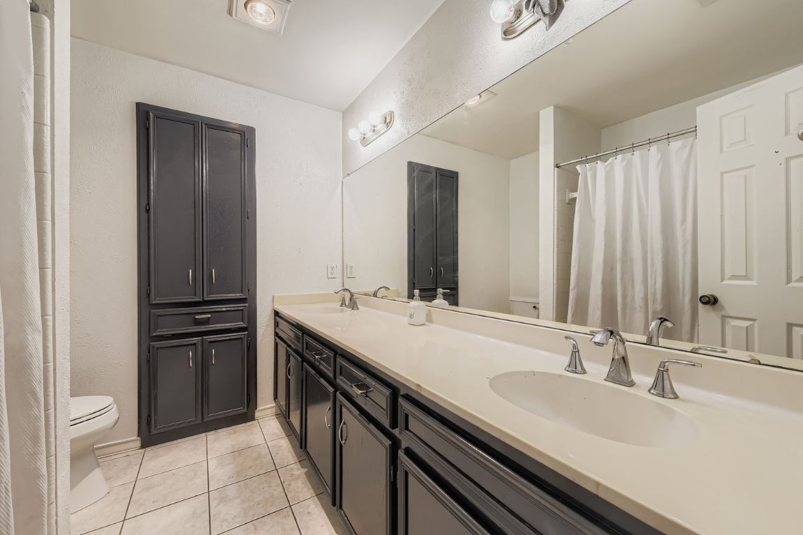 10705 Pinehurst Drive Austin, TX 78747 - Photo 20 of 30 Guest bath with dual vanities, linen cabinets, and a shower/tub combo.