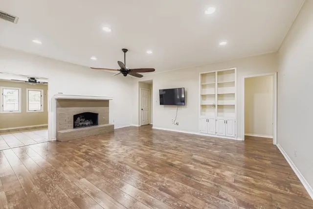 an empty room with fireplace fan and windows
