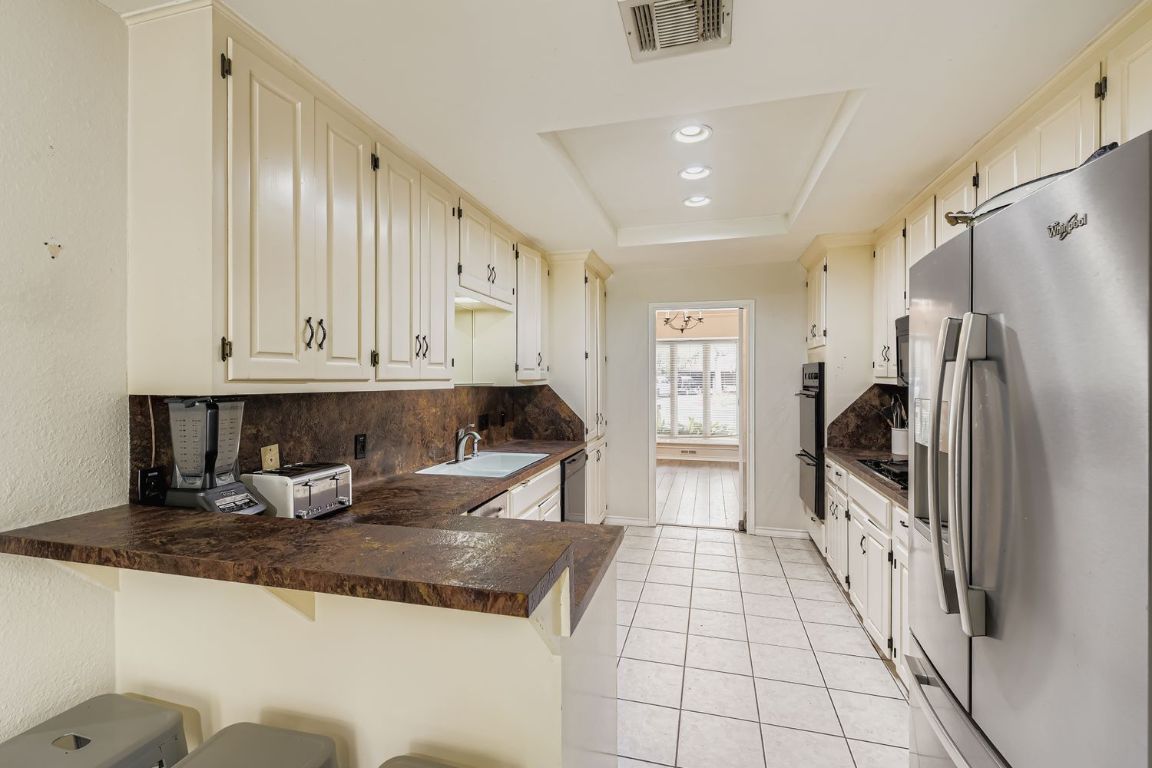 10705 Pinehurst Drive Austin, TX 78747 - Photo 10 of 30 The eat-in kitchen has a gas range, dishwasher, and a small breakfast bar.