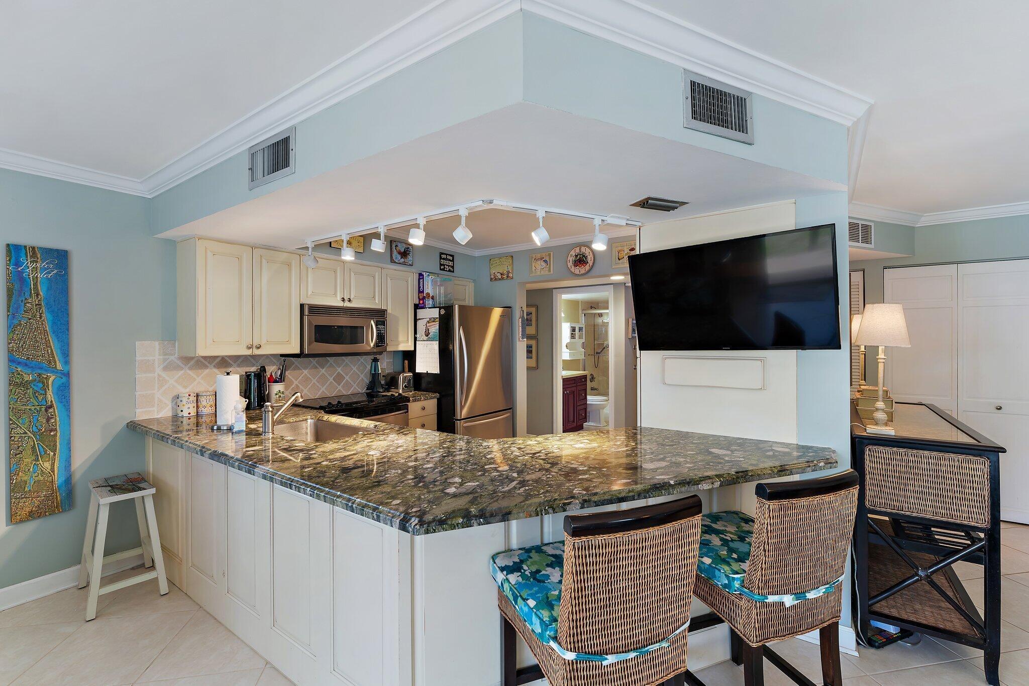 1605 Us-1, Unit B206 Jupiter, FL 33477 - Photo 12 of 35 a kitchen with granite countertop a table and chairs in it