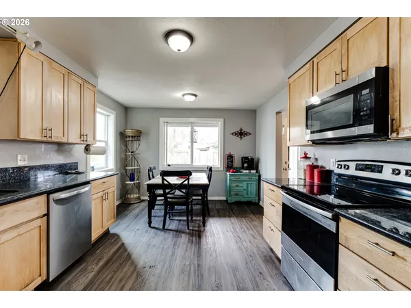 a kitchen with stainless steel appliances stove microwave refrigerator dining table and chairs