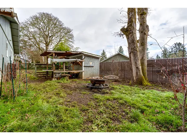 a backyard of a house with wooden fence and large trees
