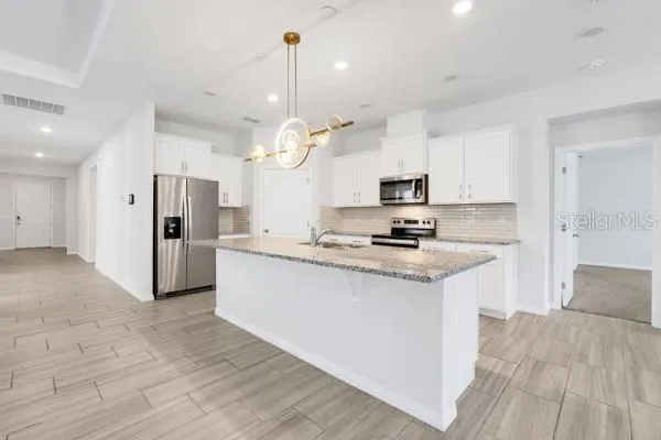 a kitchen with stainless steel appliances kitchen island granite countertop a sink a stove and a refrigerator