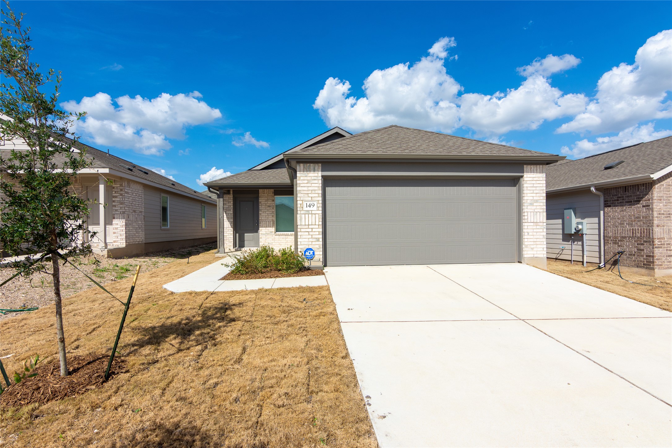 149 Star Packer Lane Jarrell, TX 76537 - Photo 2 of 30 A neatly paved driveway leads to this charming single-story residence with a gray garage door.