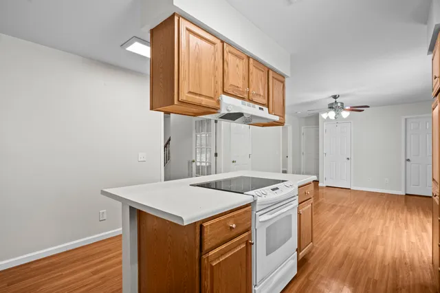 a kitchen that has a sink a microwave oven a stove and white cabinets with wooden floor