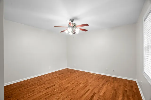 a view of a room with wooden floor and a chandelier fan