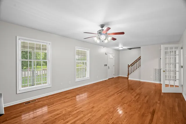 a view of an empty room with wooden floor and a window