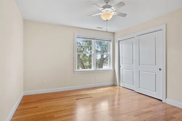 a view of empty room with wooden floor and fan