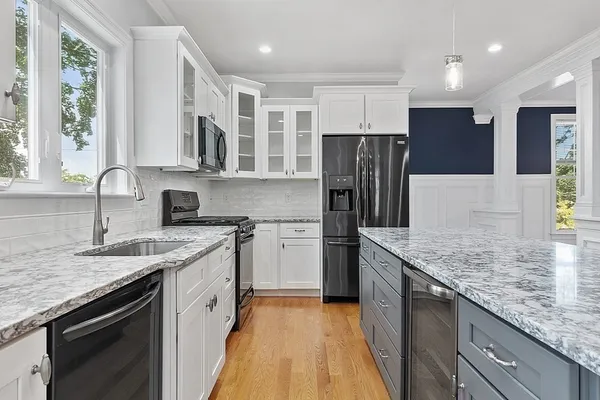 a kitchen with granite countertop a stove top oven a sink dishwasher a refrigerator and a dining table with wooden floor