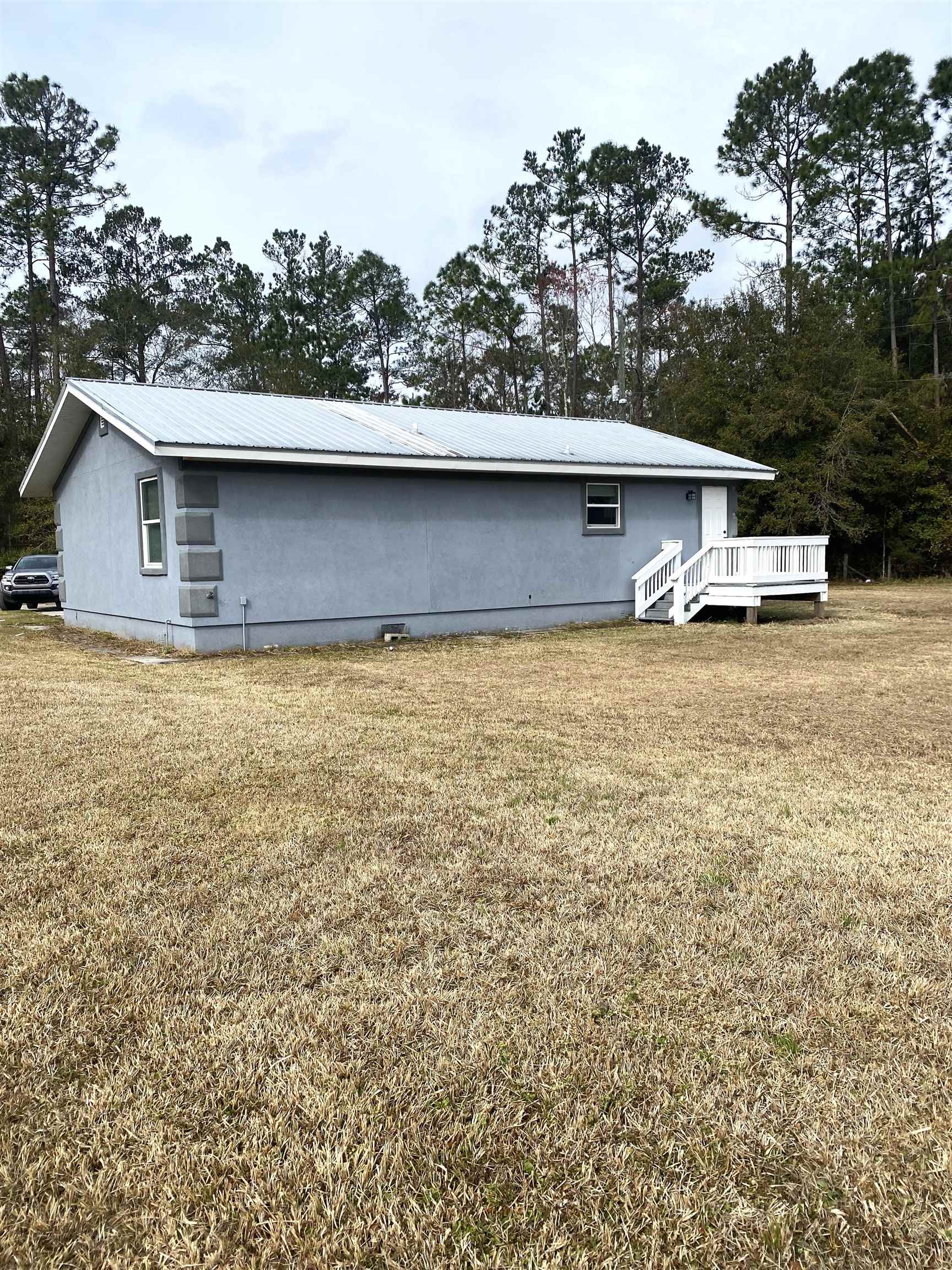 1870 Adams Acres Road St. Augustine, FL 32084 - Photo 11 of 12 View of property exterior featuring a lawn, a metal roof, and a deck