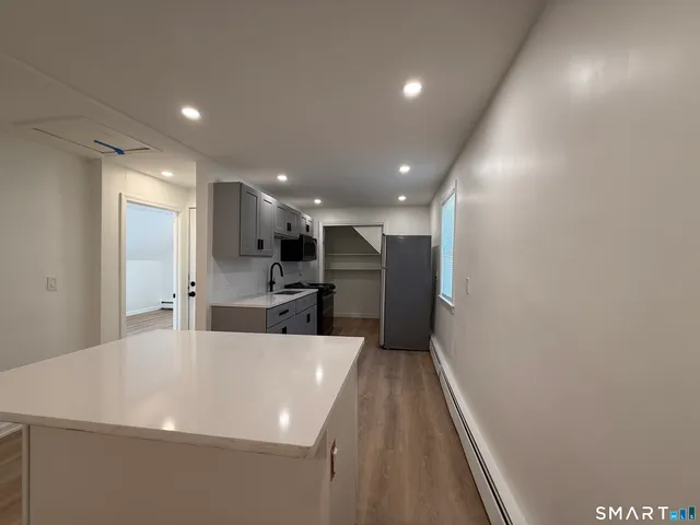 a large white kitchen with wooden floor and a refrigerator