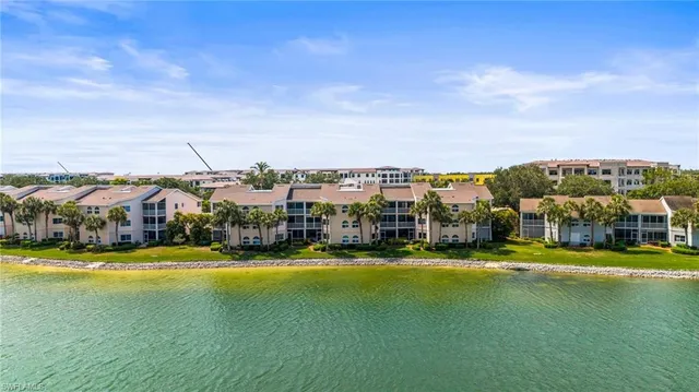 a view of a swimming pool with lawn chairs and large trees