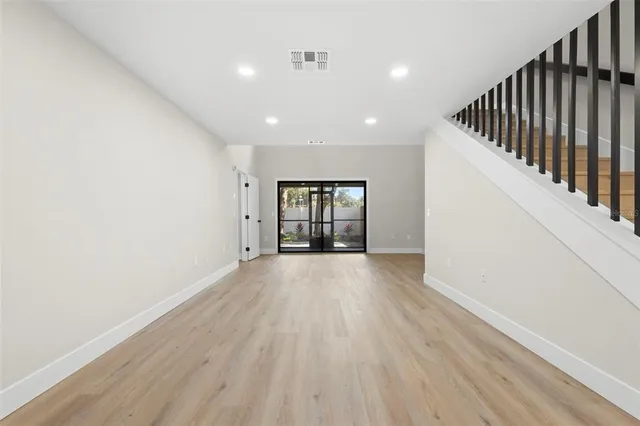 a view of an empty room with wooden floor and cabinet