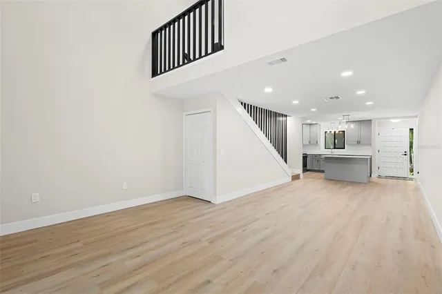 a view of an empty room with wooden floor and stairs