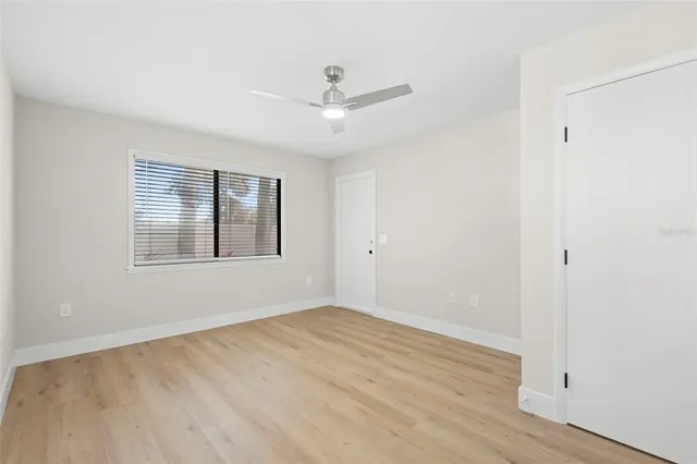 an empty room with wooden floor ceiling fan and windows