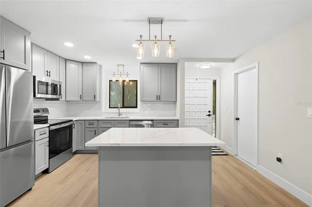 a large kitchen with a sink stainless steel appliances and cabinets