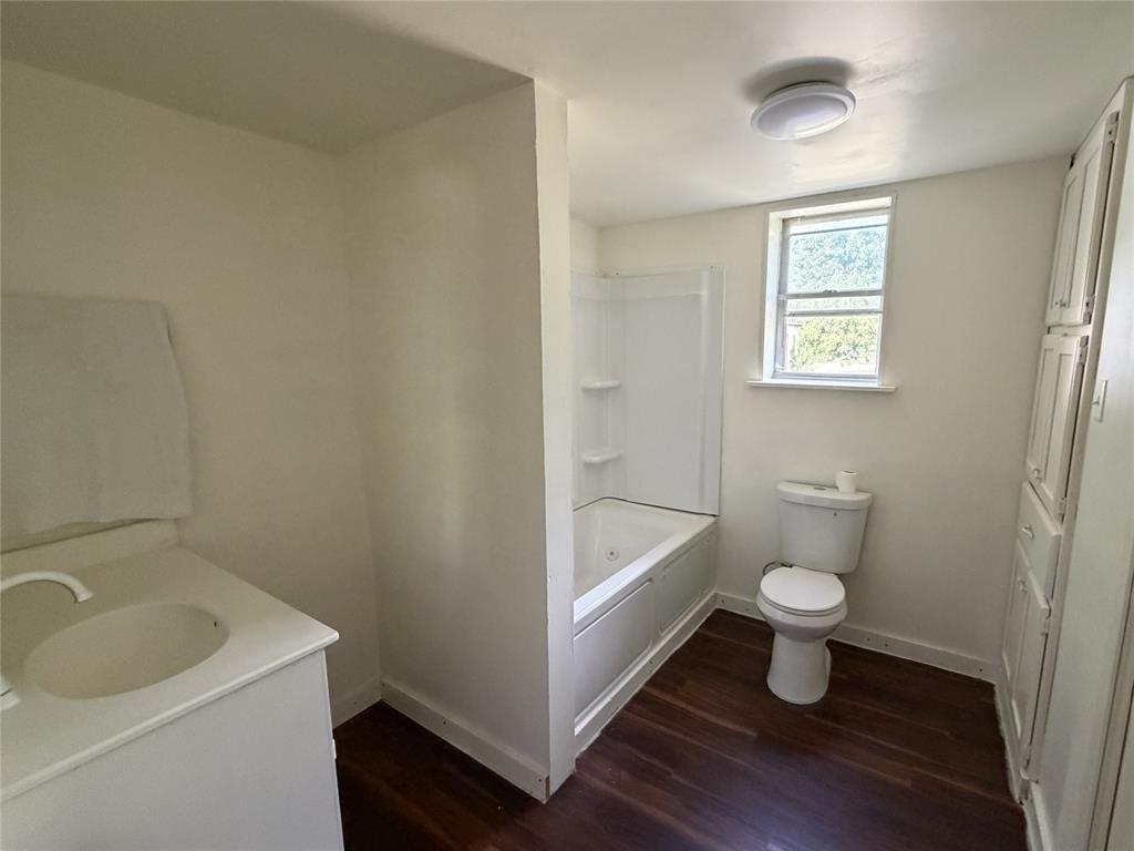 267 North Katy Road Elm Mott, TX 76640 - Photo 14 of 21 Bathroom featuring a wood-finish floor, built-in storage cabinetry, a vanity with an integrated sink, and a combination tub and shower unit