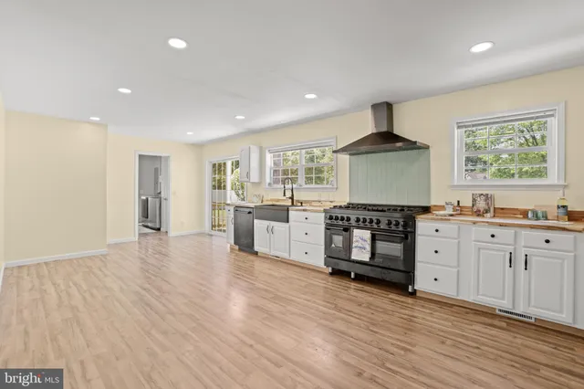 a large kitchen with cabinets wooden floor and stainless steel appliances