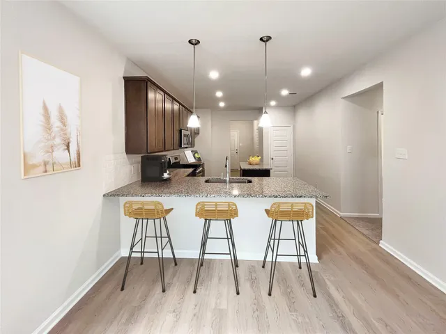 a kitchen with stainless steel appliances kitchen island granite countertop a dining table chairs and a wooden floor