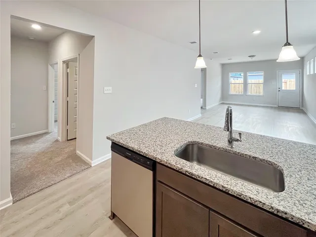 a kitchen with granite countertop a sink and a wooden floor