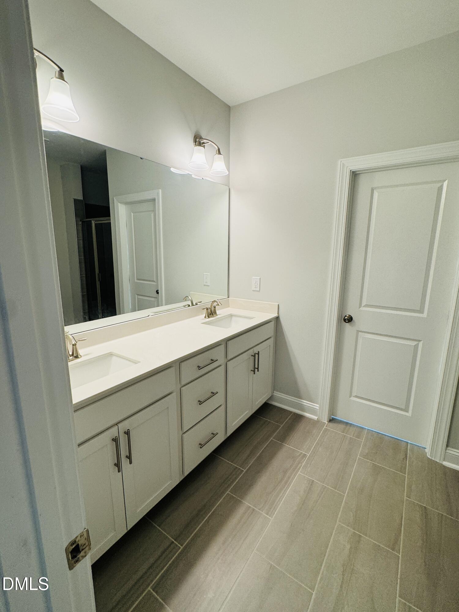 292 Edge Of Auburn Boulevard Raleigh, NC 27610 - Photo 32 of 38 a bathroom with a double vanity sink a mirror and a shower