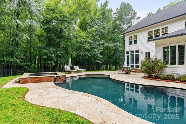 a view of swimming pool with lawn chairs and plants