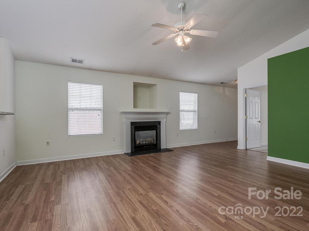 3036 Proverbs Court Monroe, NC 28110 - Photo 6 of 18 an empty room with wooden floor chandelier fan and windows