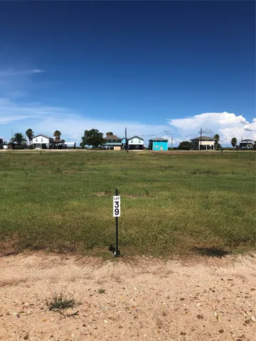 a view of a lake with beach and house in the background