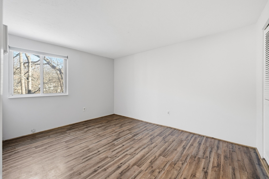 10 Mill Street, Unit Q Maynard, MA 01754 - Photo 21 of 31 an empty room with wooden floor and windows