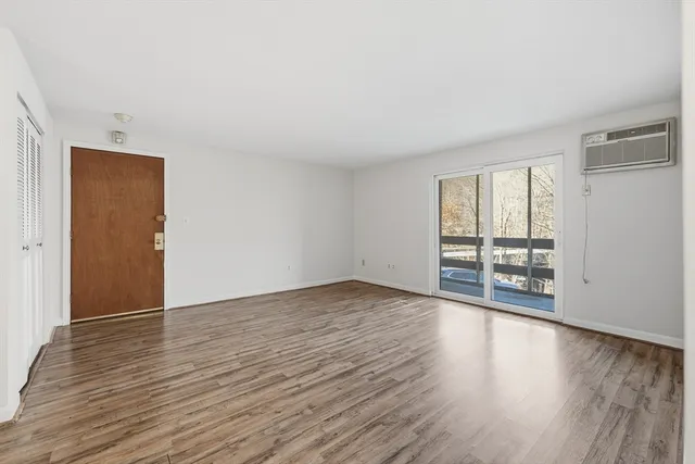 a view of an empty room with wooden floor and a window
